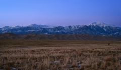 A wide-angle view of valley, sand dunes, and mountains just after sunset, with a blue and purple sky, Great Sand Dunes National Park and Preserve