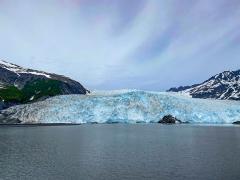 Blue-tinged ice of a glacier flowing out toward the water of Kenai Fjords National Park