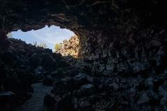 Looking back to the sunlit entrance from inside a lava tube at Lava Beds National Monument in California