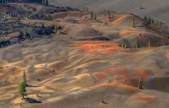 A telephoto view of colorful beige, orange, and yellow pumice dunes seen from the top of Cinder Cone in Lassen Volcanic National Park