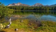 A bright, clear autumn afternoon with blue sky at a calm Manzanita Lake with Chaos Crags and Lassen Peak towering over the scene, Lassen Volcanic National Park
