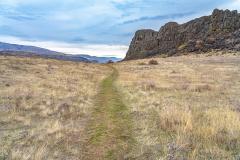 A grassy trail between a basalt outcrop known as Horsethief Butte on an overcast, autumn day at Columbia Hills Historical State Park, Lewis and Clark National Historic Trail