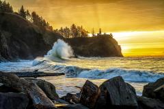 A colorful sunrise as the backdrop to high cliffs, a lighthouse, and king tide wave action at Cape Disappointment State Park along the Louis and Clark National Historic Trail