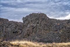The tiny figures of three people standing atop the basalt outcrop of Horsethief Butte on an overcast day at Columbia Hills Historical State Park along the Lewis and Clark National Historic Trail