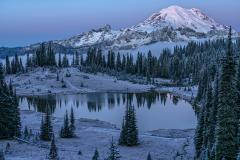 A snowy view of Tipsoo Lake and Mount Rainier as the morning sun begins to lightly shine on the snowcapped mountain top, Mount Rainier National Park