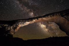 The arching rock formation known as Owachomo Bridge frames this view of the Milky Way overhead at Natural Bridges National Monument, Utah.