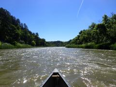 The Niobrara NSR as seen from a canoe, with tree-lined bluffs and a deep blue sky