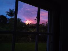 The bright glow in the early morning hours created from Mauna Loa's eruption as  seen from the silhouetted window of a home in Hilo, Hawaii