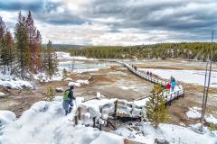 People carefully walking down the snow-and-ice-packed boardwalk into Porcelain Basin, a part of the Norris Basin complex, Yellowstone National Park