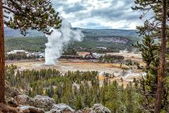 A view of an erupting Old Faithful Geyser, surrounded by the Old Faithful building complex at Upper Geyser Basin in Yellowstone National Park