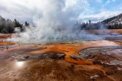 A heavily-steaming Emerald Pool surrounded by orange bacterial mats at Black Sand Basin in Yellowstone National Park