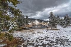 A cloudy, snowy morning with steaming hot springs along the Firehole River in Upper Geyser Basin, Yellowstone National Park