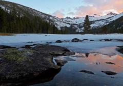 Sunset alpenglow on the mountains above reflections on a frozen lake in Upper Lyell Canyon, Yosemite National Park